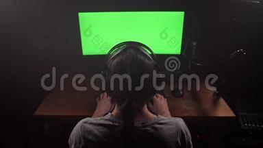一个戴着耳机的人看着显示器的绿色屏幕，摘下耳机，看着屏幕，开始打字